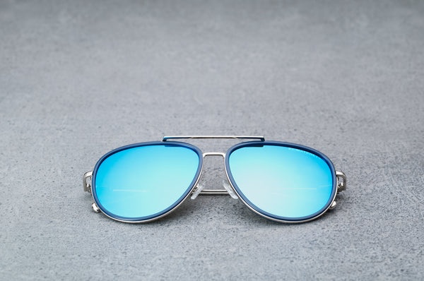 Silver aviator style sunglasses with reflective blue lenses, laying flat, facing forward.