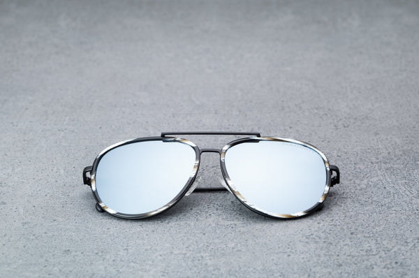Black patterned sunglasses with reflective silver lenses , laying flat, facing foward.