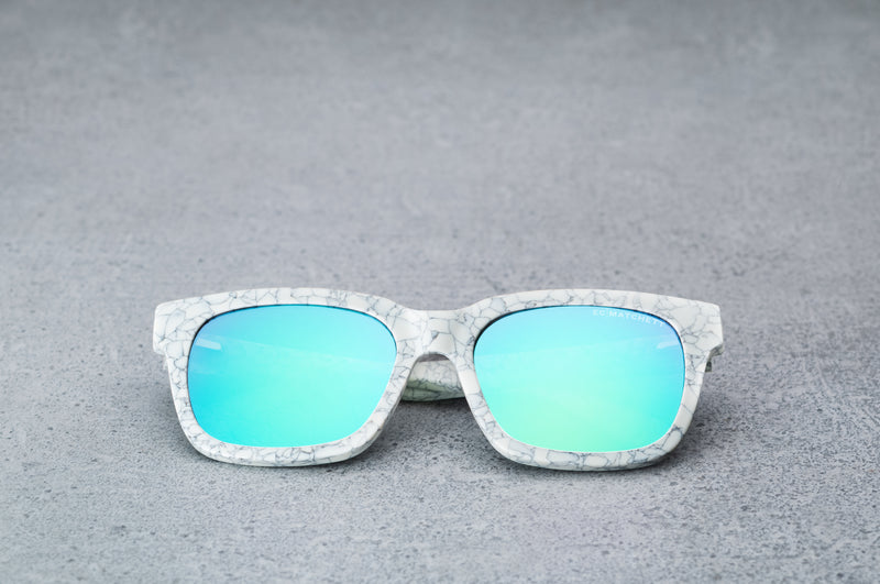 White patterned sunglasses with reflective blue lenses laying flat, facing forward.