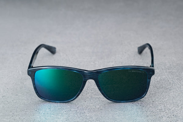 dark blue sunglasses with reflective green lenses, open, facing forward.