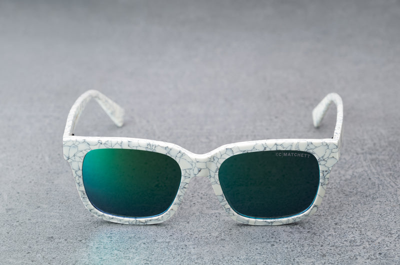 White patterned sunglasses with reflective blue lenses, facing forward with temples open..