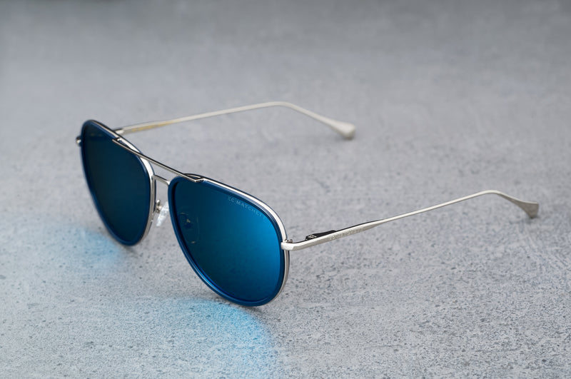 Silver aviator style sunglasses with reflective blue lenses, open, facing left showing a quartering view.