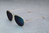 Gold aviator style sunglasses with reflective green lenses open, facing to the left showing a quartering view.
