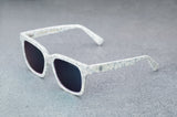 White patterned sunglasses with reflective blue lenses , facing to the left giving a quartering view..