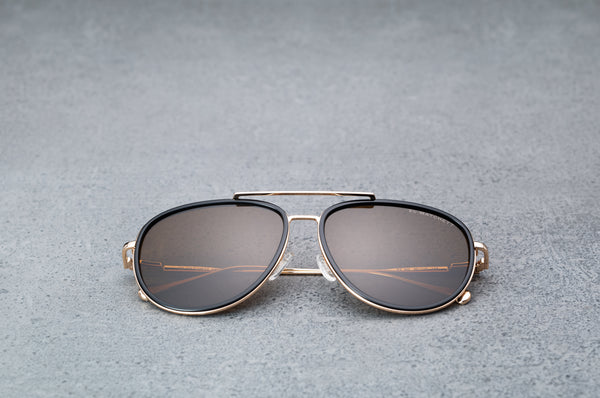 Gold aviator style sunglasses with dark brown lenses  laying flat, facing forward.