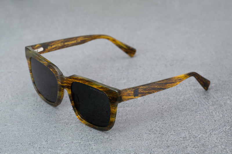 Black and amber patterned sunglasses with black lenses, facing to the left.