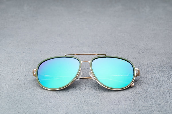 Gold aviator style sunglasses with reflective green lenses  laying flat, facing forward.