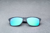 dark blue sunglasses with reflective green lenses, laying flat, facing forward.