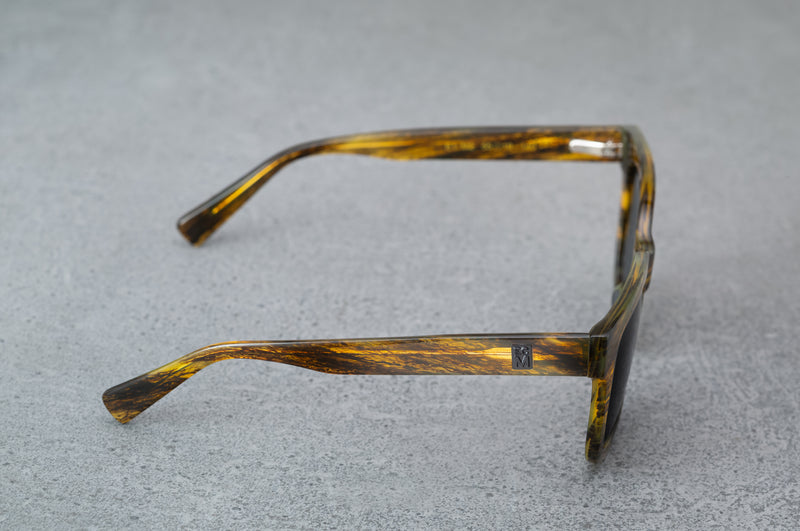 Black and amber patterned sunglasses, facing to the ride giving a side view.
