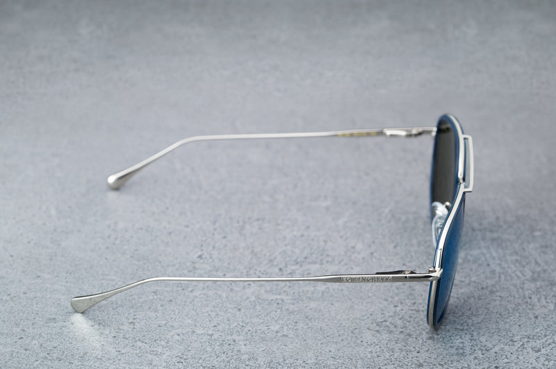 Silver aviator style sunglasses with reflective blue lenses, open, facing right showing the frames.