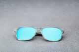 Light green sunglasses with reflective blue lenses, laying flat, facing forward.