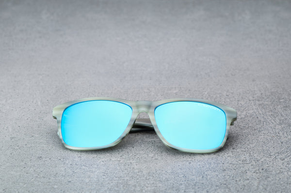 Light green sunglasses with reflective blue lenses, laying flat, facing forward.